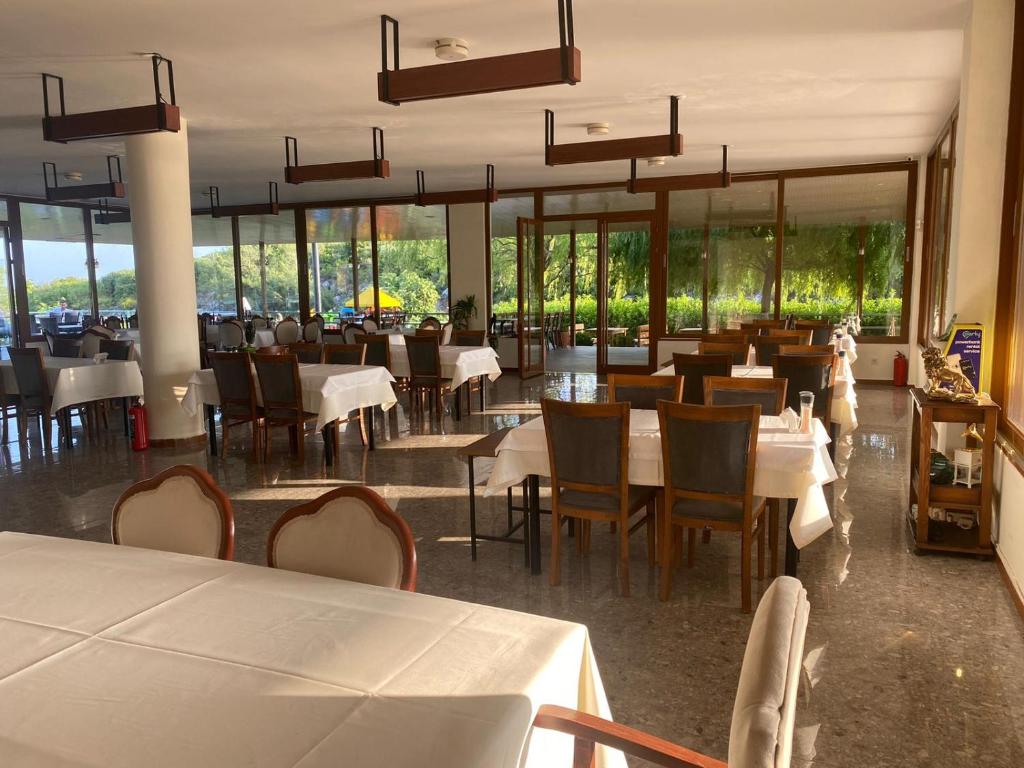 乌尔拉Zu Tiny House Hotel & Restaurant的餐厅设有白色的桌椅和窗户。