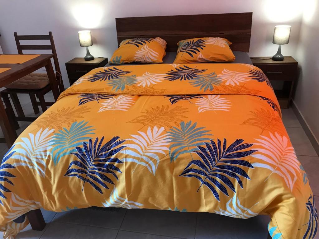 马罗尼河畔圣洛朗Discrétion的一张带橙色床罩的床,上面有棕榈树