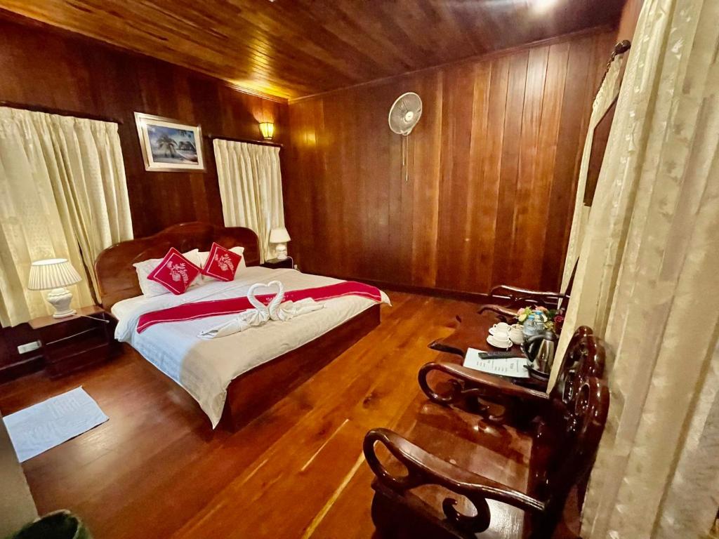 琅勃拉邦帕莎纳精品酒店的一间卧室设有床铺、木墙和木地板