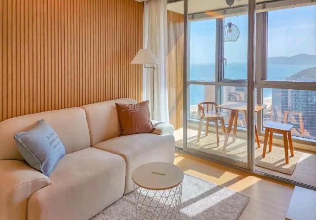 釜山premium ocean view in HAEHUNDAE BONA TRAVEL的客厅配有白色的沙发和桌子