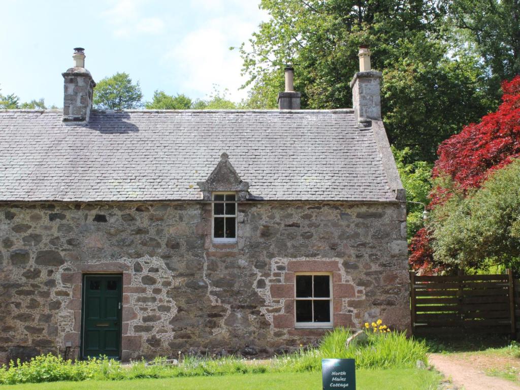 AlfordNorth Mains Cottage - Craigievar Castle的一座带绿门的古老石屋