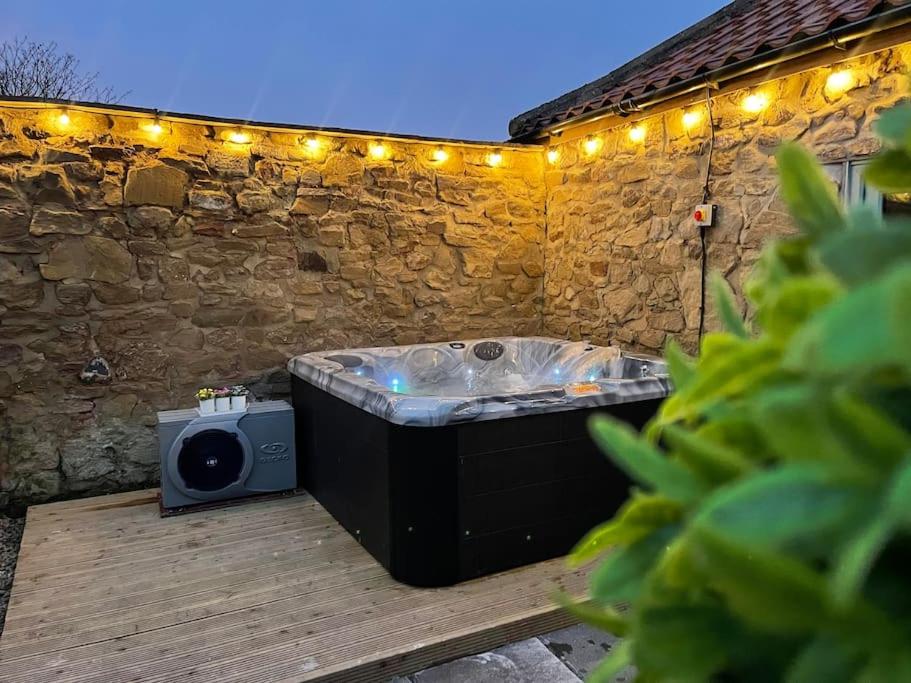 蒂斯河畔斯托克顿The Old Moat Barn - With Private Hot Tub的木甲板上设有热水浴池,配有灯