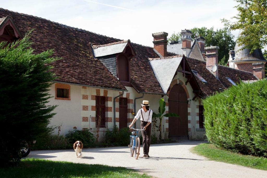 谢韦尔尼Cottages et B&B de Troussay的房屋前有自行车和狗的人