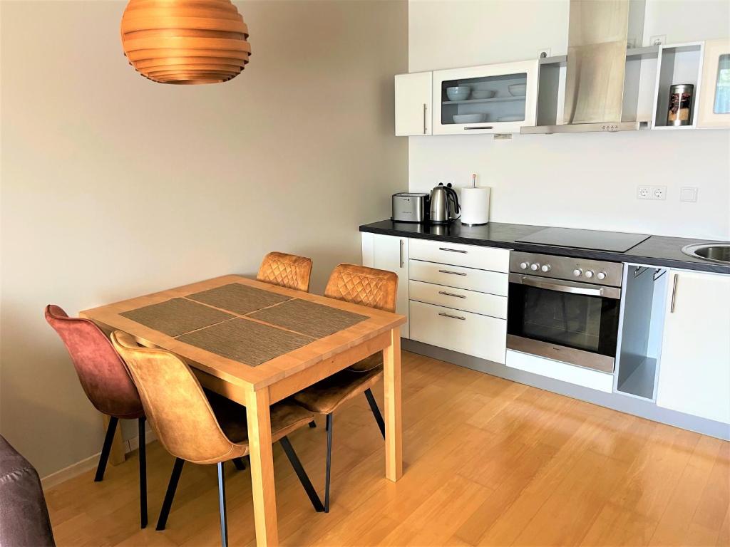 库雷萨雷Kuressaare Holiday Apartments的厨房配有木桌和一些椅子