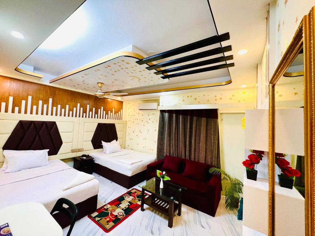 达卡HOTEL BLUE BIRD的酒店客房带两张床和一张红色沙发