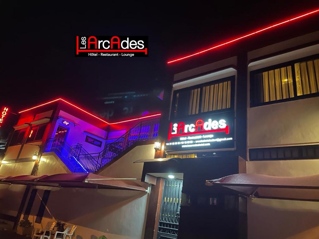 科托努HOTEL LES ARCADES的建筑的侧面有 ⁇ 虹灯标志