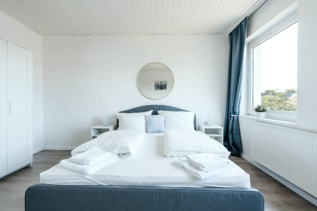 霍尔斯泰因地区诺伊斯塔特Geräumige 2-Zimmer-Wohnung的白色的客房内的一张大白色床,设有窗户