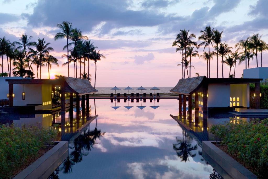 蔻立JW Marriott Khao Lak Resort Suites的棕榈树和海洋的度假游泳池