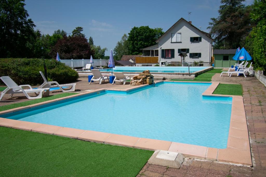 Saint-Honoré-les-BainsCamping des Bains的一个带椅子的游泳池和一个背景房子