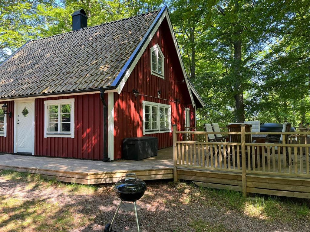 Skånes FagerhultBlueberry Hill的红色的房子,设有甲板和烧烤架