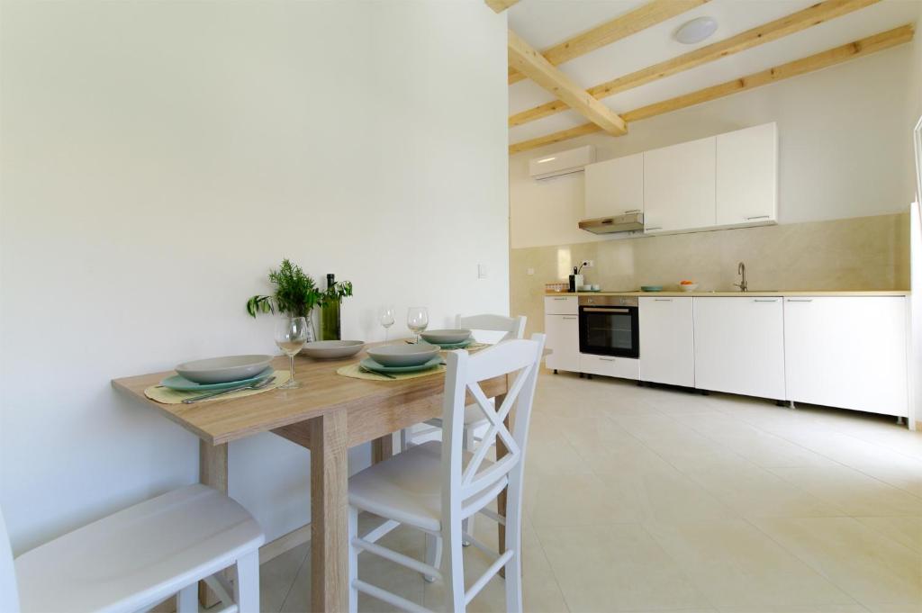 萨利Apartmani Porat Sali的厨房配有木桌和白色橱柜。