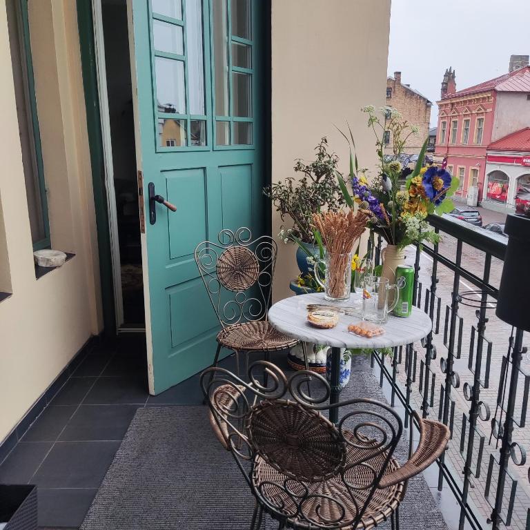 文茨皮尔斯Ventspils apartamenti pie Rātslaukuma的阳台配有一张桌子和椅子,阳台设有蓝色的门