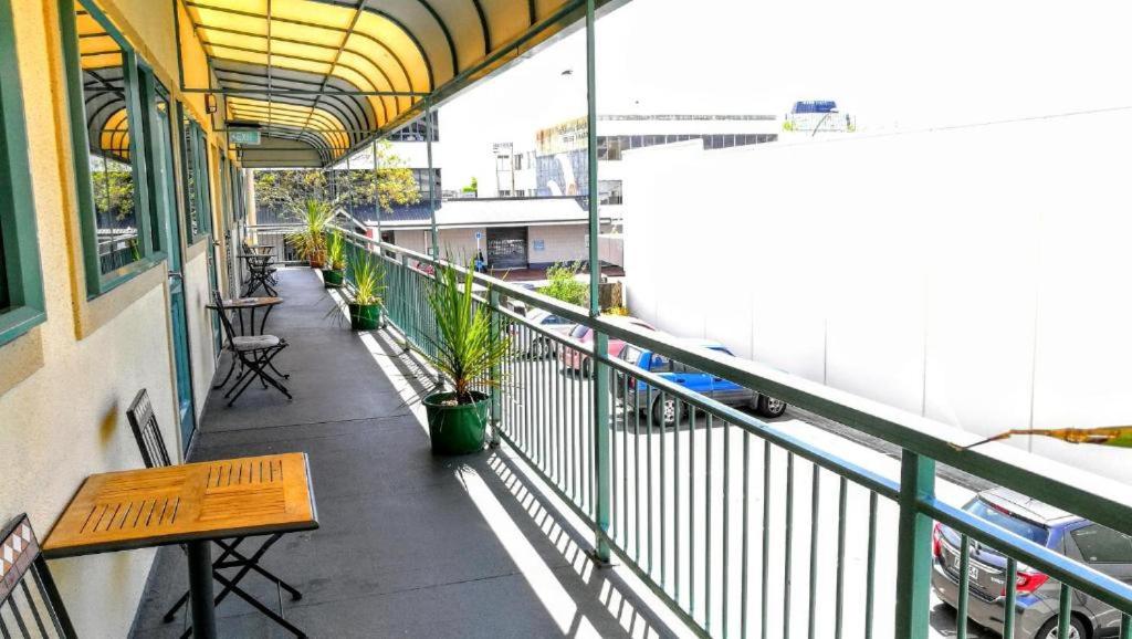 罗托鲁瓦Stay Hostel Rotorua的大楼内的阳台配有长凳和桌子