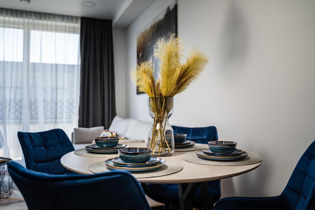 维尔纽斯Lazdyneliu Vingis的一张带蓝色椅子的餐桌和一个带羽毛的花瓶