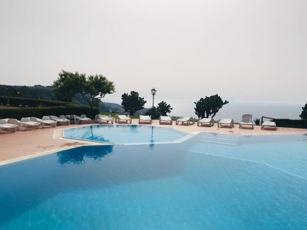帕尔盖利亚Marasusa Apartments Scirocco的一个带椅子的大型蓝色游泳池,并享有海景