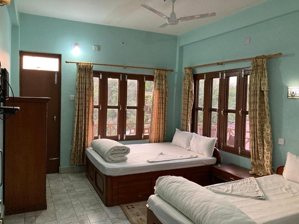 索拉哈Sauraha Guest House的一间卧室设有两张床和两个窗户。
