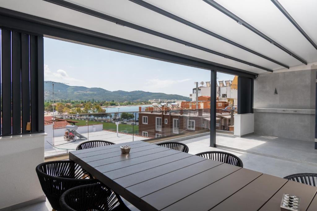 新马尔马拉斯SithoniaRS Luxury 2nd Floor Roofgarden Apartment With Unique Seaview的阳台配有木桌、椅子和大窗户。
