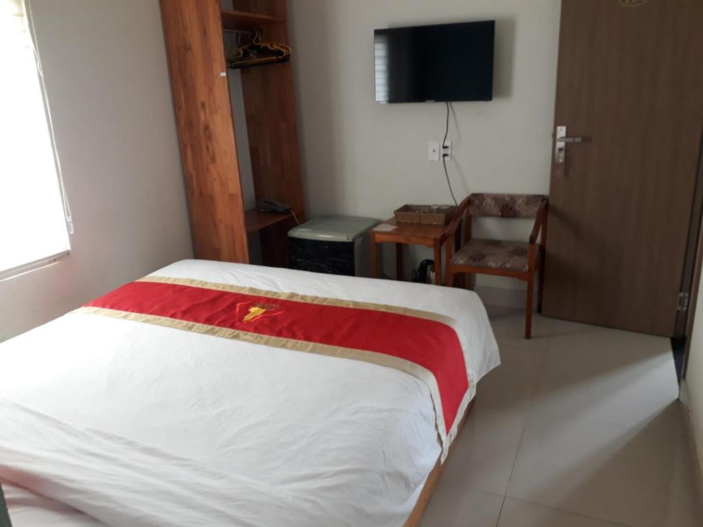 Phú Khê (2)Hotel Bảo Quang的一间卧室配有一张床、一把椅子和电视