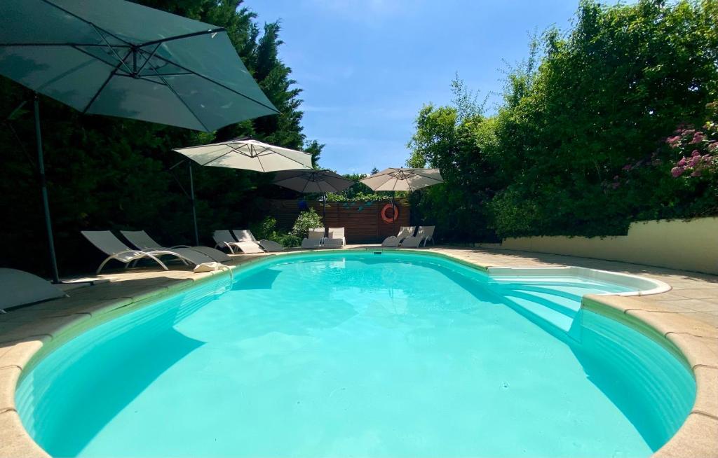 萨尔拉拉卡内达Le Petit Prince à Sarlat - Parking privé - piscine chauffée - espace bien-être Jacuzzi et massages的一个带椅子和遮阳伞的大型蓝色游泳池