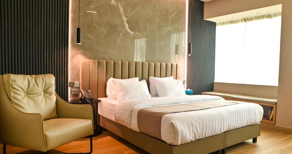 拉各斯Vertigo Hotel的一间卧室配有一张大床和一把椅子