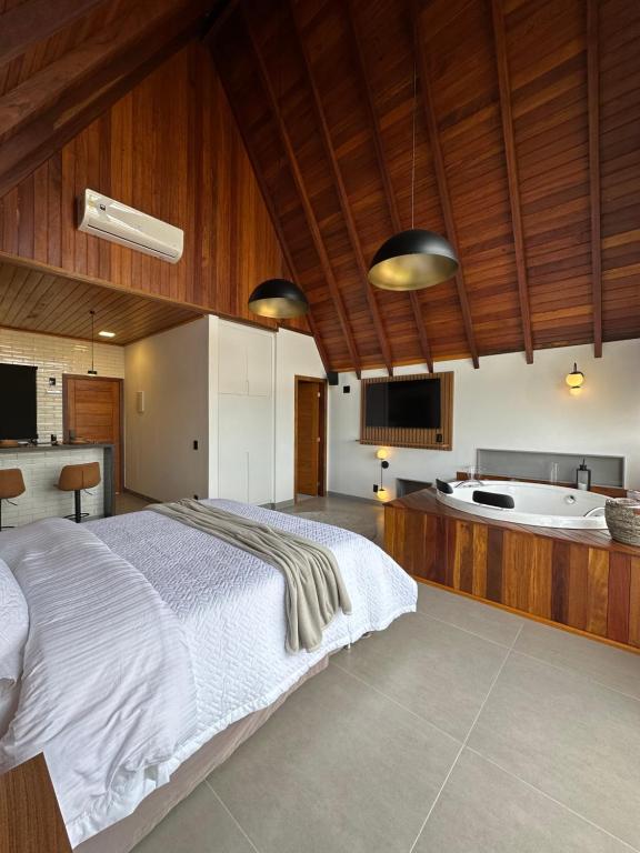 新文达移民镇Chalés Laguna Alto Viçosa的一间卧室设有一张大床和一个浴缸