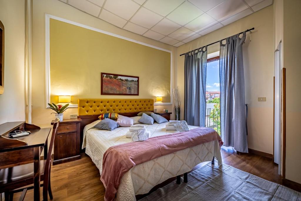 比萨密涅瓦酒店的一间卧室配有一张床、一张书桌和一个窗户。