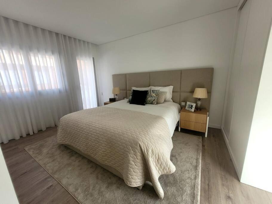 吉马良斯Cidade_Berço House的白色卧室配有一张大床和两盏灯。