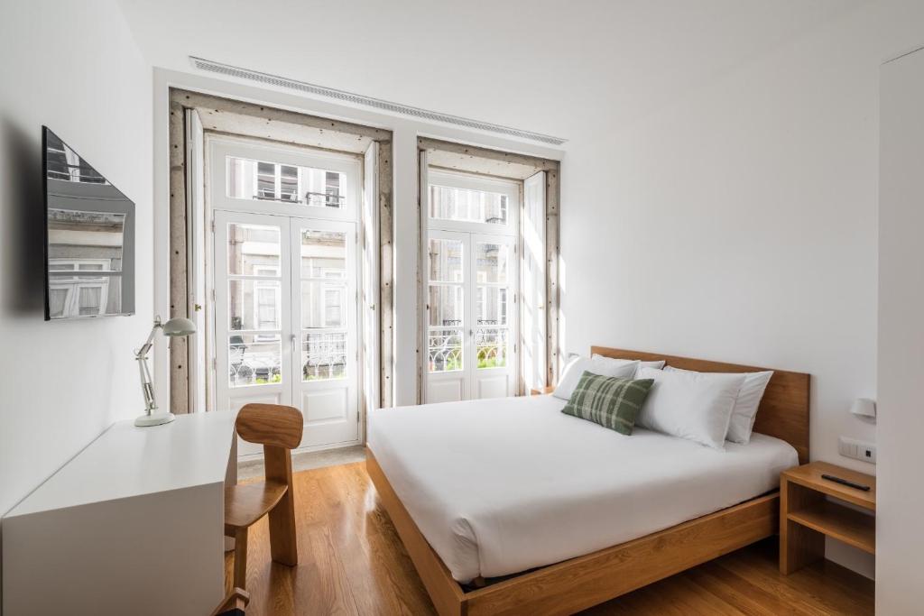 维亚纳堡Avenida Viana Boutique Suites的一间卧室配有一张床、一张书桌和两个窗户。