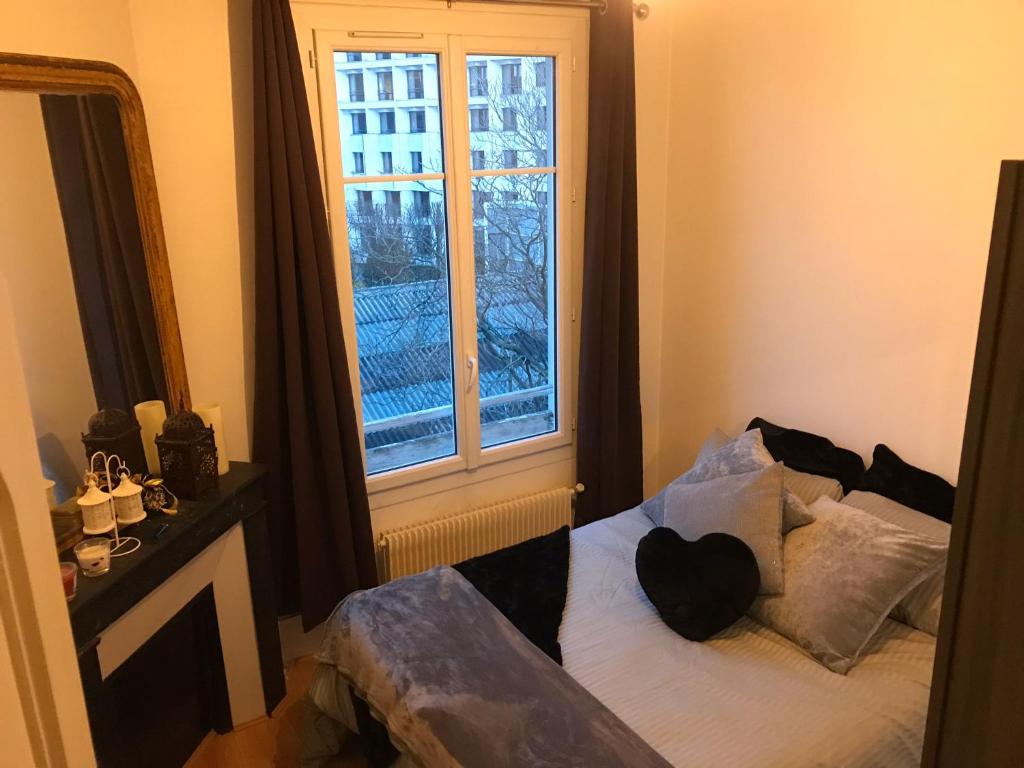 布洛涅-比扬古Appartement 60 m², porte de Saint-Cloud的卧室在窗户前配有一张床