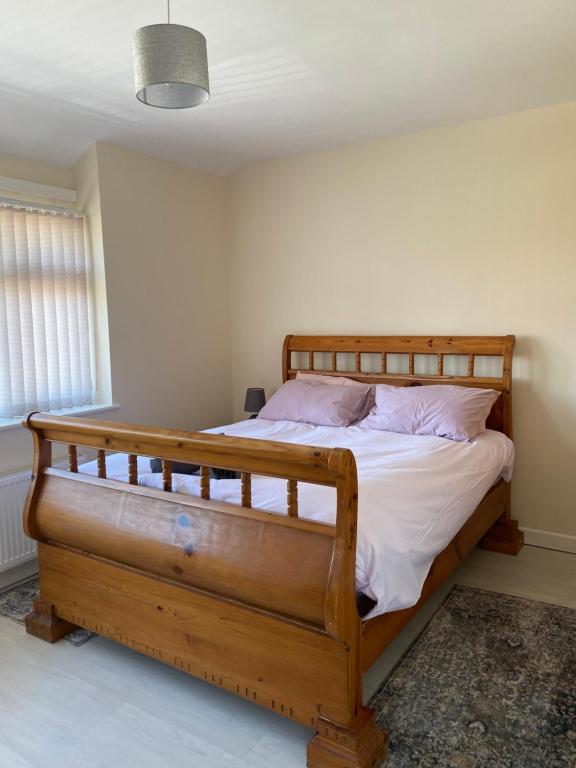 曼彻斯特Greenwood的一间卧室配有带白色床单和粉红色枕头的木制床。