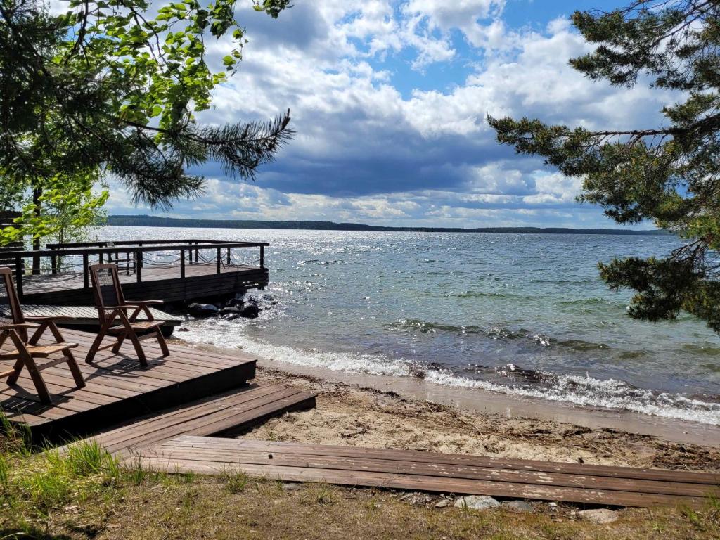 KesälahtiLakeland Karelia Puutikka的海滩上带长凳和椅子的码头