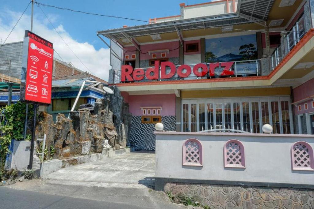 沃诺索博RedDoorz near Desa Wisata Tambi Dieng的粉红色建筑物前的红色门道标志