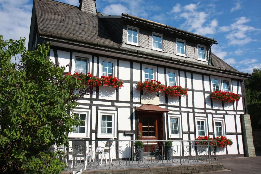 施马伦贝格Landhaus Gnacke的白色和黑色的建筑,窗户上装有红色的鲜花