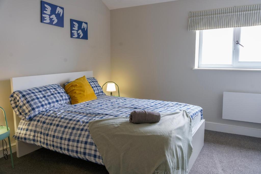 伦敦Stunning New 2 Bed Flat - 6 August House的一间卧室配有一张带黄色枕头的床和一扇窗户