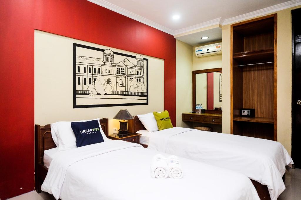 日惹Urbanview Hotel Syariah Wisnugraha by RedDoorz的红色墙壁的客房内的两张床