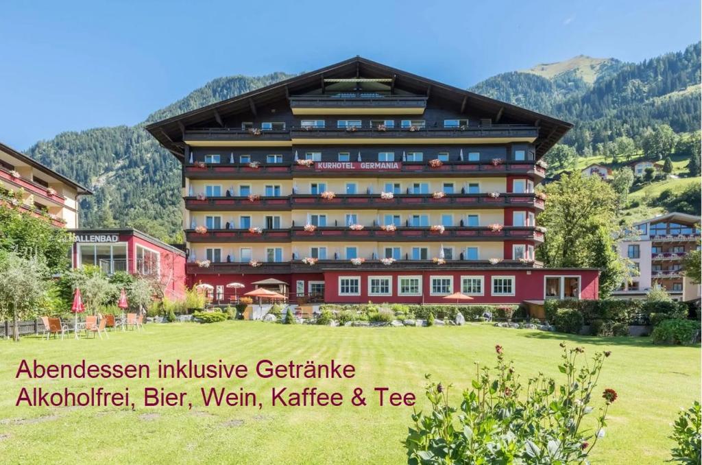 巴特霍夫加施泰因Hotel Germania Gastein - ganzjährig inklusive Alpentherme Gastein & Sommersaison inklusive Gasteiner Bergbahnen的前面有绿地的大建筑