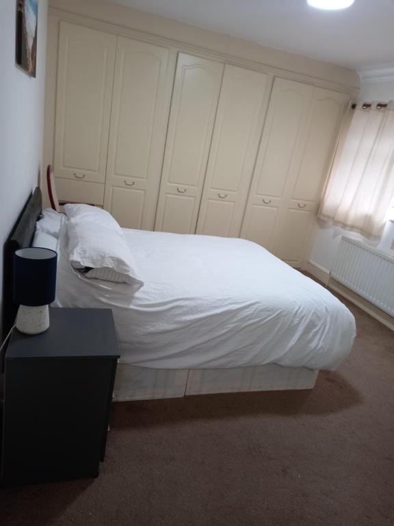 Streatham ValeSandra的一间卧室配有一张带白色床单和一张桌子的床。