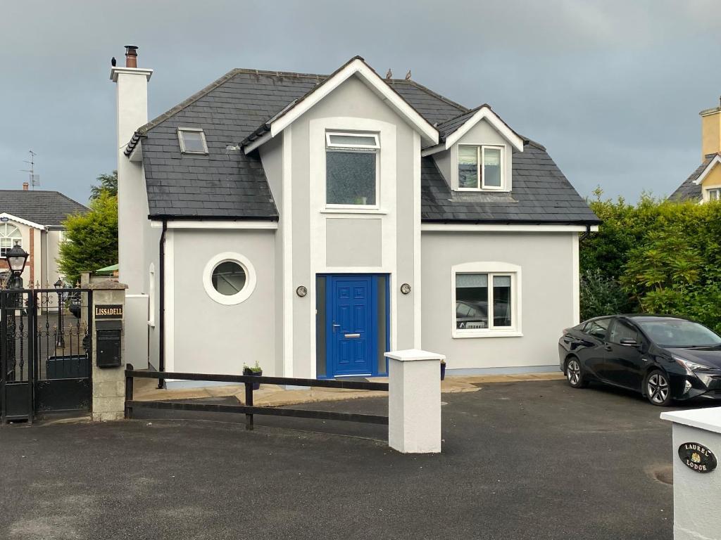Droichead an ChaisleáinLaurel Lodge的停车场内有蓝色门的白色房子