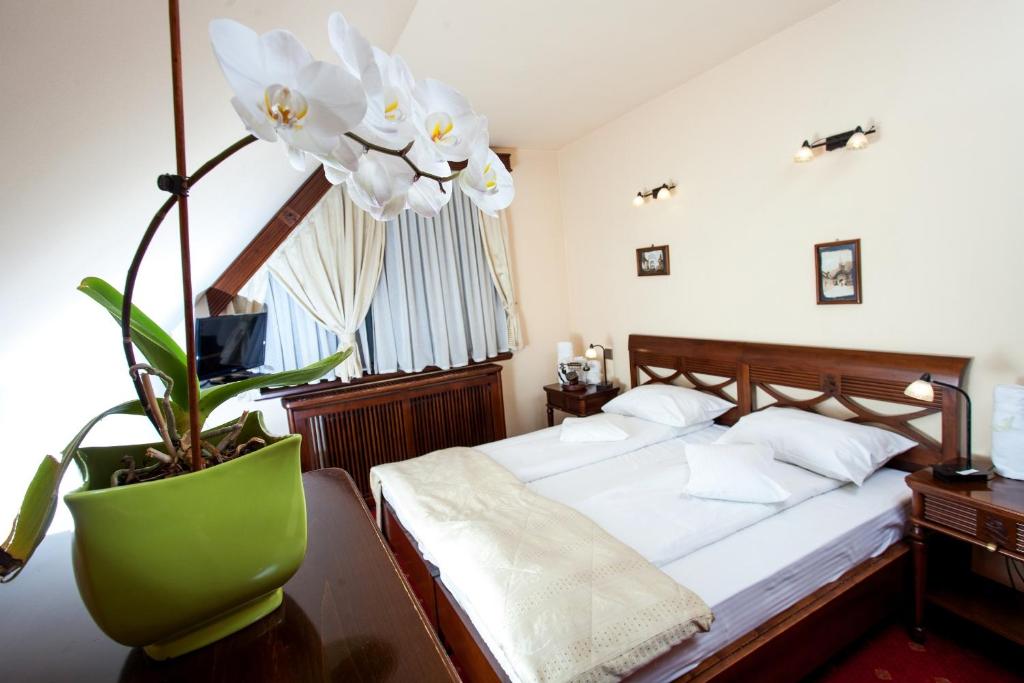 布拉索夫老布拉索夫酒店的一间卧室,配有床和花瓶中的植物