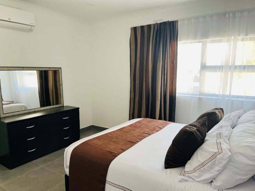 哈博罗内Comfy Zone Apartment的一间卧室配有一张带镜子和梳妆台的床