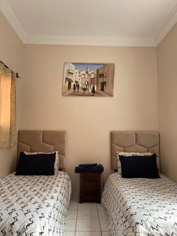 马拉喀什Riad Nour Travel-Les Riads Nour Resorts的卧室配有两张床,墙上挂着一幅画