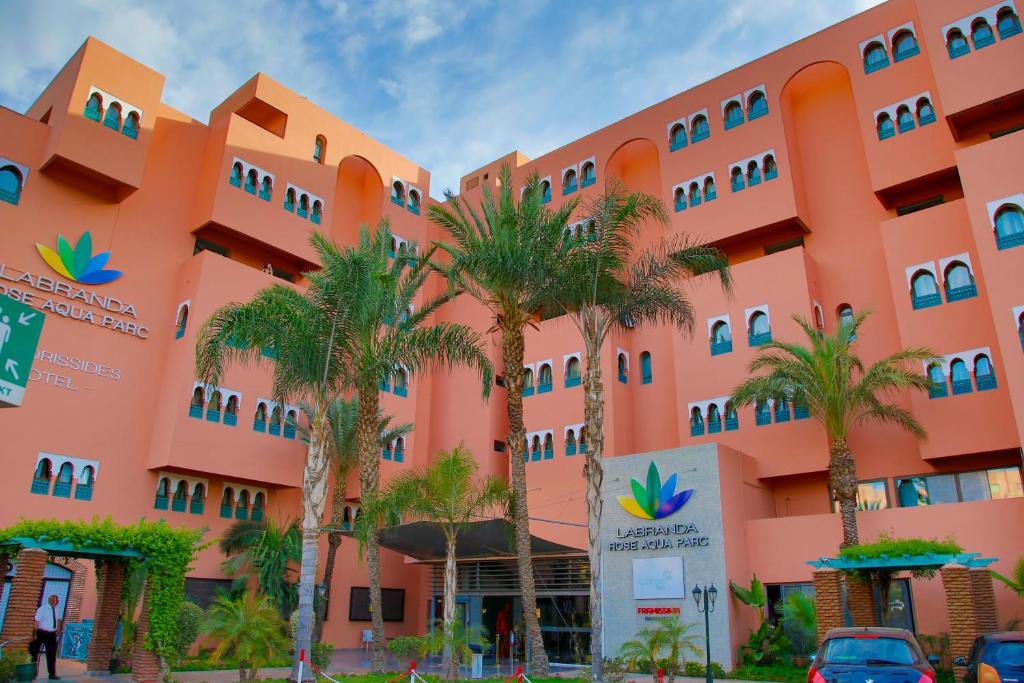 马拉喀什Labranda Rose Aqua Parc的一座种植了棕榈树的橙色建筑