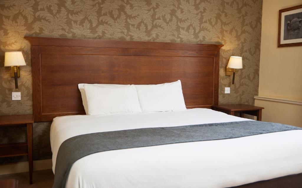塞特福德Bell by Greene King Inns的一间卧室配有一张大床和木制床头板