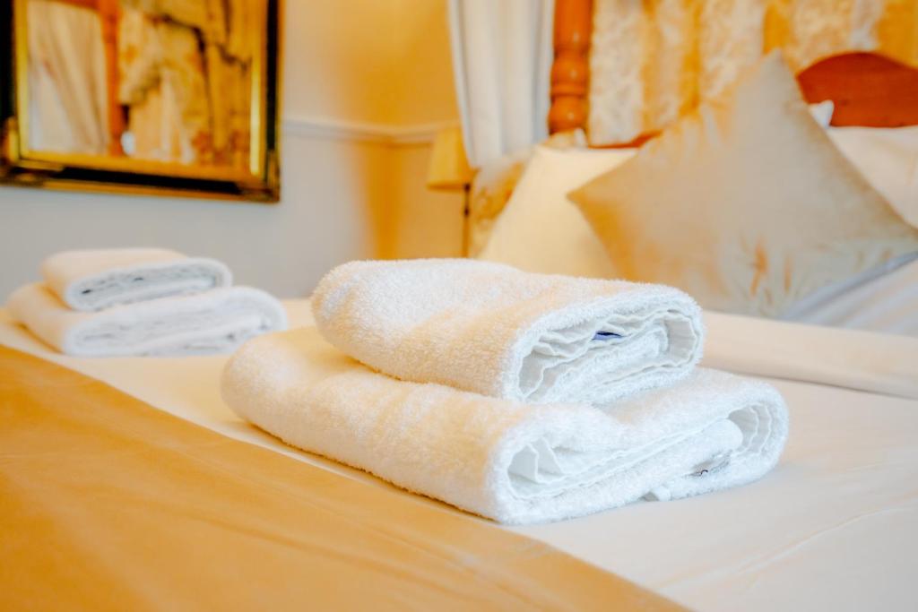 布洛克利Crown Hotel Cotswold的两条毛巾被堆在床上