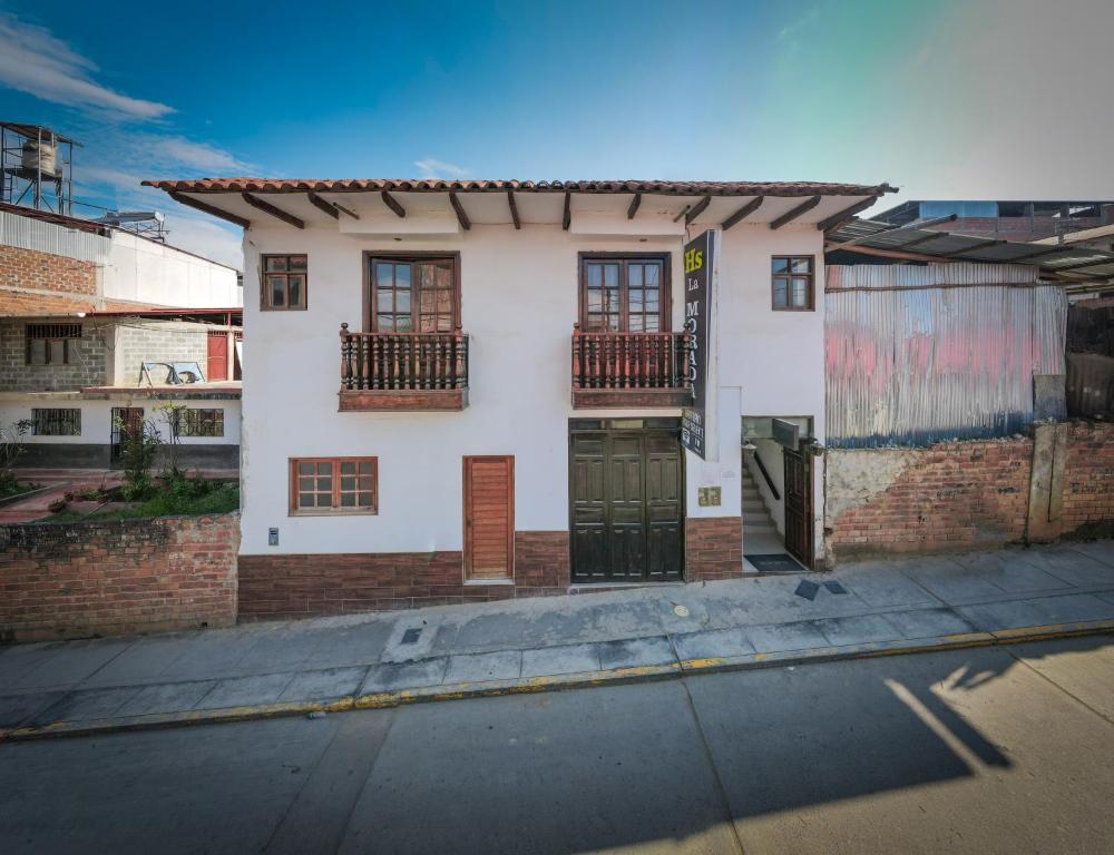 查查波亚斯Hostal La Morada的白色的房子,有窗户和一扇门在街上