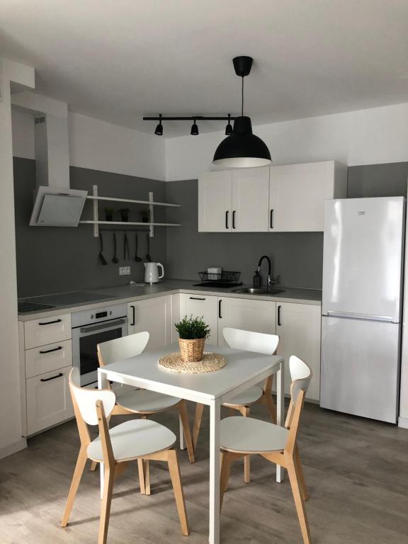 霍伊尼采Apartament Skandynawski的厨房配有桌椅和白色冰箱。