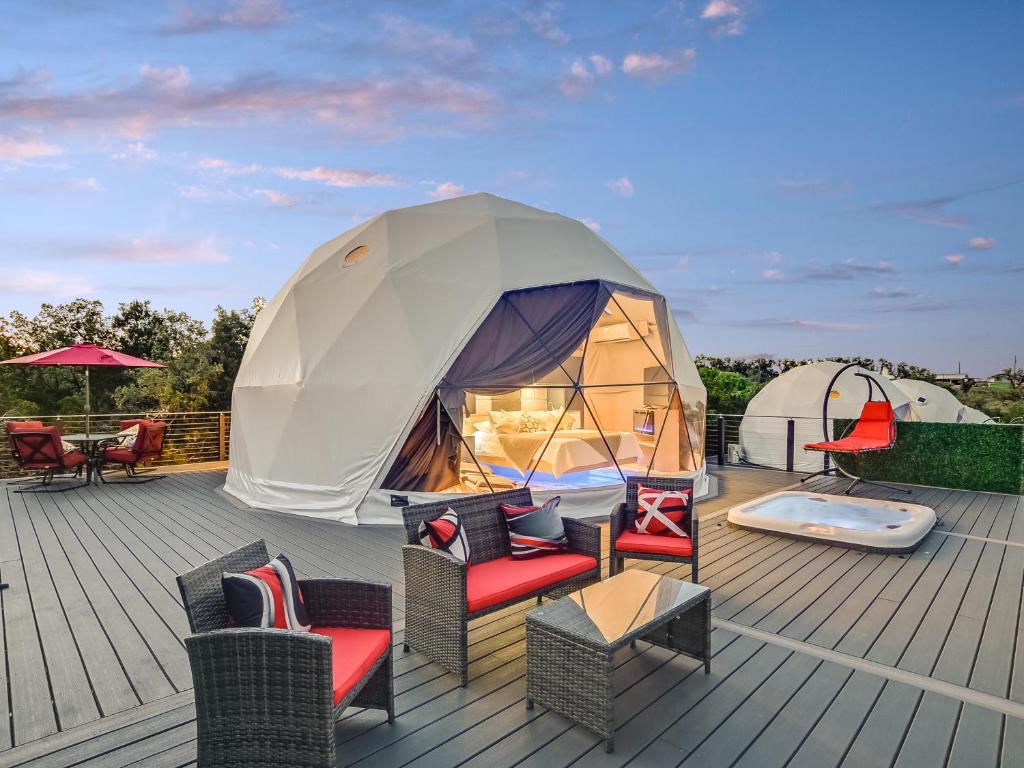 Lago VistaUdoscape Eco-Glamping Resorts的甲板上的大型帐篷,配有桌椅