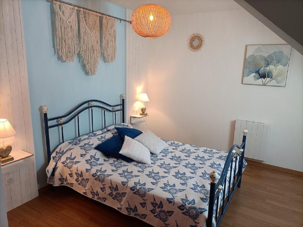CahagnesLe Moulin de Benneville chambres d'hôtes, petit déjeuner compris的一间卧室配有一张带蓝色和白色棉被的床