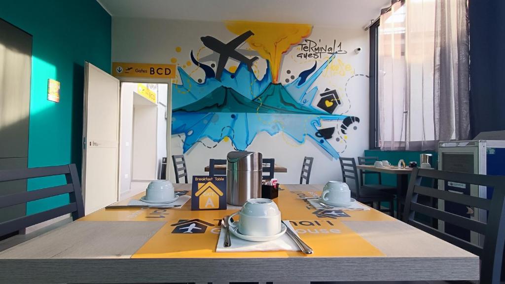 那不勒斯Terminal 1 Guest House的用餐室配有一张桌子,墙上挂着一幅画