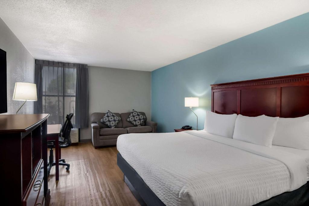 大急流城Clarion Inn and Suites Airport的酒店客房设有一张大床和一张书桌。